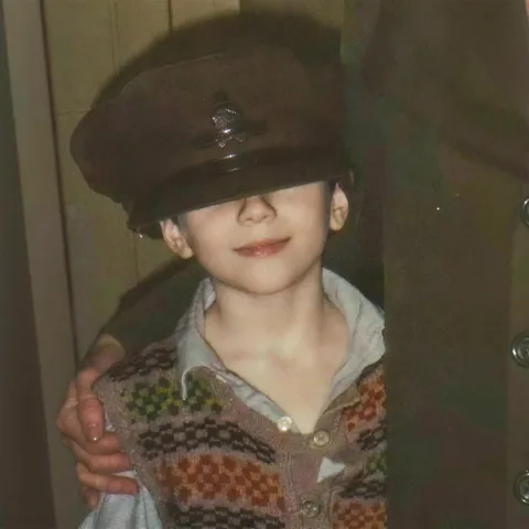 Karim as a child, lifting his cap